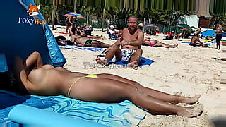 Tomando el sol en topless en la playa para ser observada por otros hombres